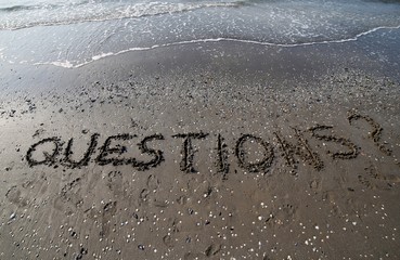 Fototapeta premium Questions with question mark written in large letters on the san