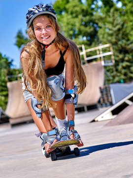 Teen wearing skateboard helmet skateboard on his skateboard and low crouch above her skateboard outdoor. Skateboard girl style.