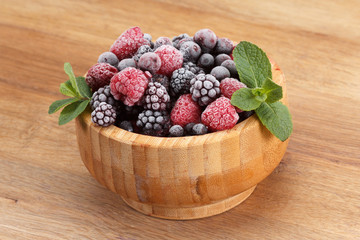 Frozen berries in wooden bowl, covered with ice