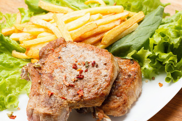 Juicy roasted pork steak with french fries and spices
