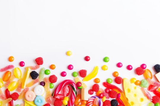 Mixed colorful candies, jellies and lolly pops on the white background. Top view with copy space