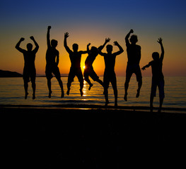 Gruppe springender Personen im Gegenlicht vor Sonnenuntergang