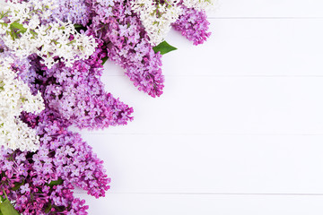 The purple and white lilac flowers on a white wooden table