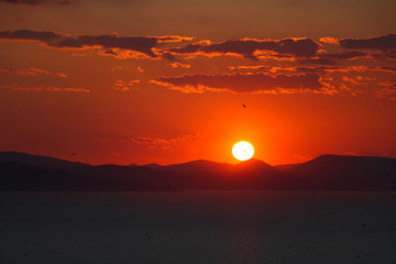 Naklejka premium Sunset above mountains at sea