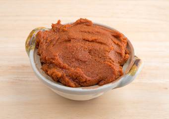 Red curry paste in a small bowl on  a wood counter top.