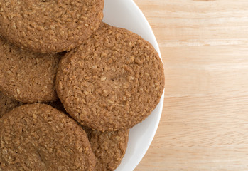Oatmeal sugar free cookies on a white plate atop a wood table top close view.