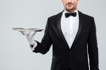 Closeup of waiter in tuxedo and gloves holding silver tray