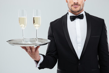 Glasses of champagne on tray holded by waiter in tuxedo