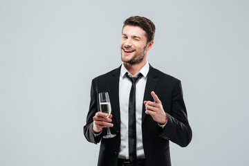 Happy handsome young businessman drinking champagne and pointing on you