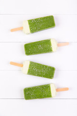 Frosty popsicles of kiwi in a row on a white wooden background