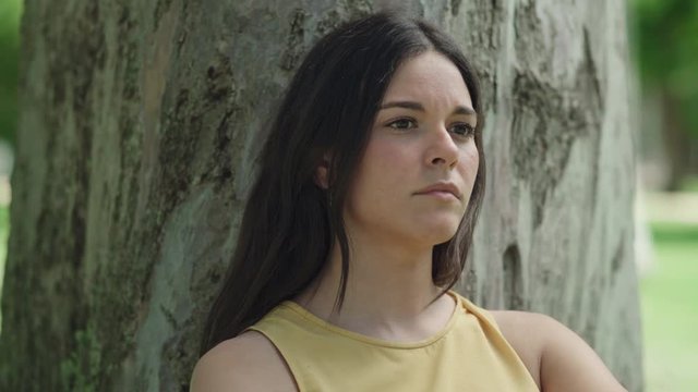 Young woman thinking upset in the park. Close up. Dolly shot