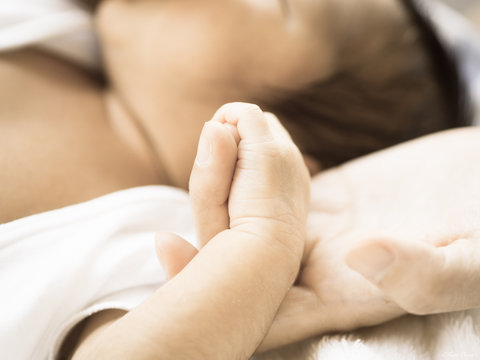 A baby holds mum's hand