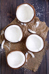 Fresh coconut halves with shell on a dark wooden table. Top view