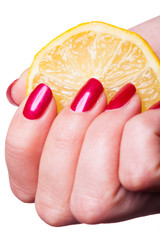 Hand with manicured nails squeeze lemon on white