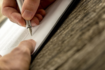 Low angle closeup view of male hand signing contract