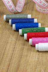 Line of colourful threads with a tape on the light wooden background