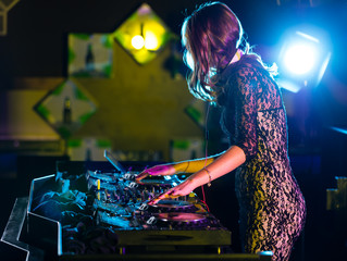 Obraz na płótnie Canvas Disc jockey girl mixing electronic music in club