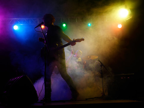 Silhouette of guitar player on stage.