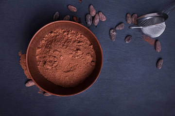 Cocoa powder in a bowl on the black background