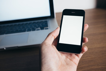 Close up of man hands with smartphone and laptop on wooden table