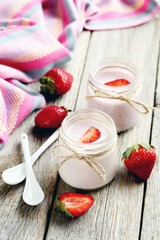Strawberry yogurt in glass on a grey wooden table