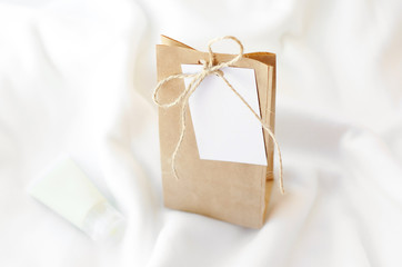 Package of kraft paper with tag for recording on a soft white blanket next to the tube of cream