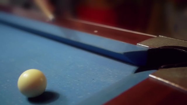 POV of pool shot on a vintage worn out blue cloth pool table in slow motion. Sports game of billiards / 8 ball. Closeup of the 11 ball that goes in.