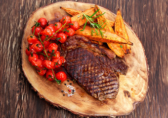 Grilled Beef Sirloin Steak on wooden board with vegetables.
