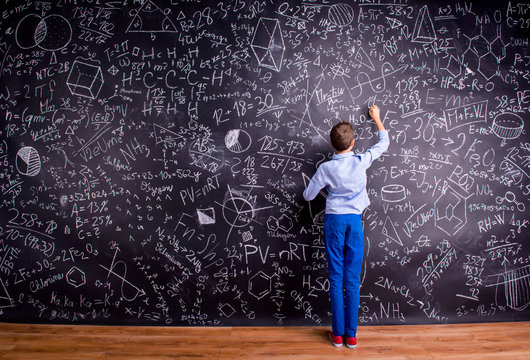 Boy against big blackboard with mathematical symbols and formula - Powered by Adobe