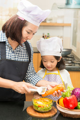 Asian mother teaching daughter making salad in kitchen,Cooking  concept of happy asian little girl and mother making salad 