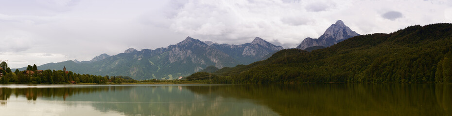 Naklejka na ściany i meble Lake in the German Alps with a chain of mountain peaks on the horizon. Reflection of the sky in water