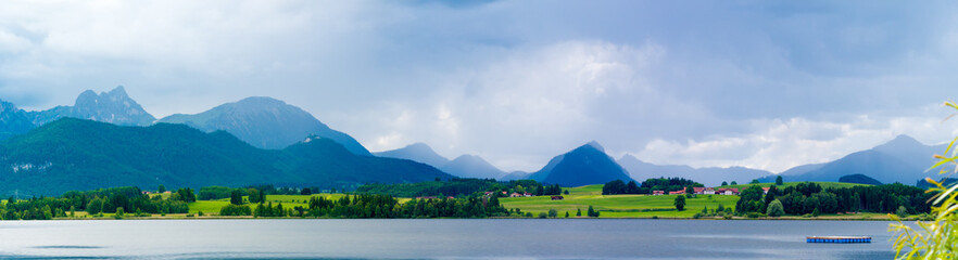 Lake in the German Alps with a chain of mountain peaks on the horizon. Reflection of the sky in water