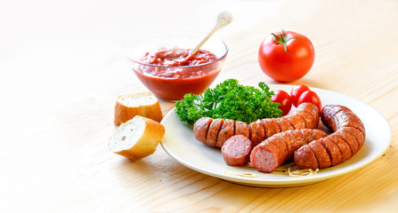 Roasted sausage with bread, herbs, sauce and tomatoes served on white plate and wood board