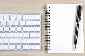 blank notebook and pen with keyboard