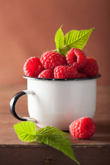 fresh raspberry in enamel cup over wooden background