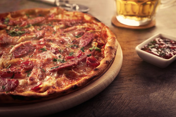 Tasty pizza and glass of beer are on wooden table, close up