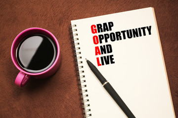 Goal Acronym - text on notebook with a pen and cup of coffee
