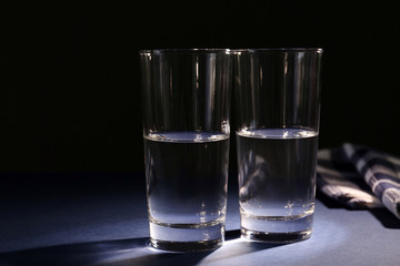 Two glasses of pure water on dark background