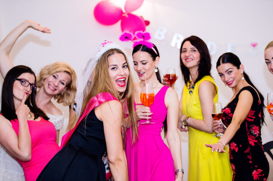 Cheerful bride and bridesmaids celebrating hen party with drinks