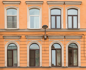 Fototapeta na wymiar Several windows in a row and streetlight on facade of urban apartment building front view, St. Petersburg, Russia.
