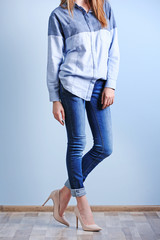 Beautiful young woman in shirt and jeans on blue wall background