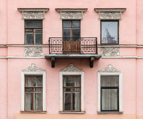 Fototapeta na wymiar Several windows in a row and balcony on facade of urban apartment building front view, St. Petersburg, Russia.