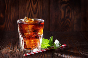 Cola drink. Cola with ice in a glass on a background of vintage boards
