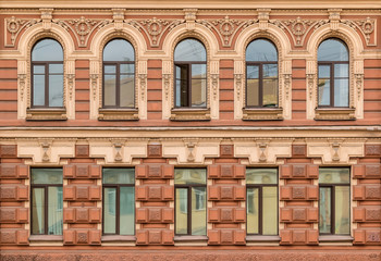 Several windows in a row on facade of urban apartment building front view, St. Petersburg, Russia.