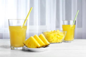 Glass of sweet juice and sliced pineapple on the table