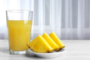 Glass of sweet juice and sliced pineapple on the table