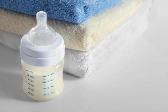 Baby bottle with milk and soft towels isolated on white