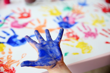 Child making hand print on bright blurred background