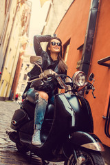 Naklejka premium Brunette female posing on motor scooter.