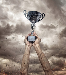 Fototapeta premium Cropped hand of athlete holding trophy against epic background